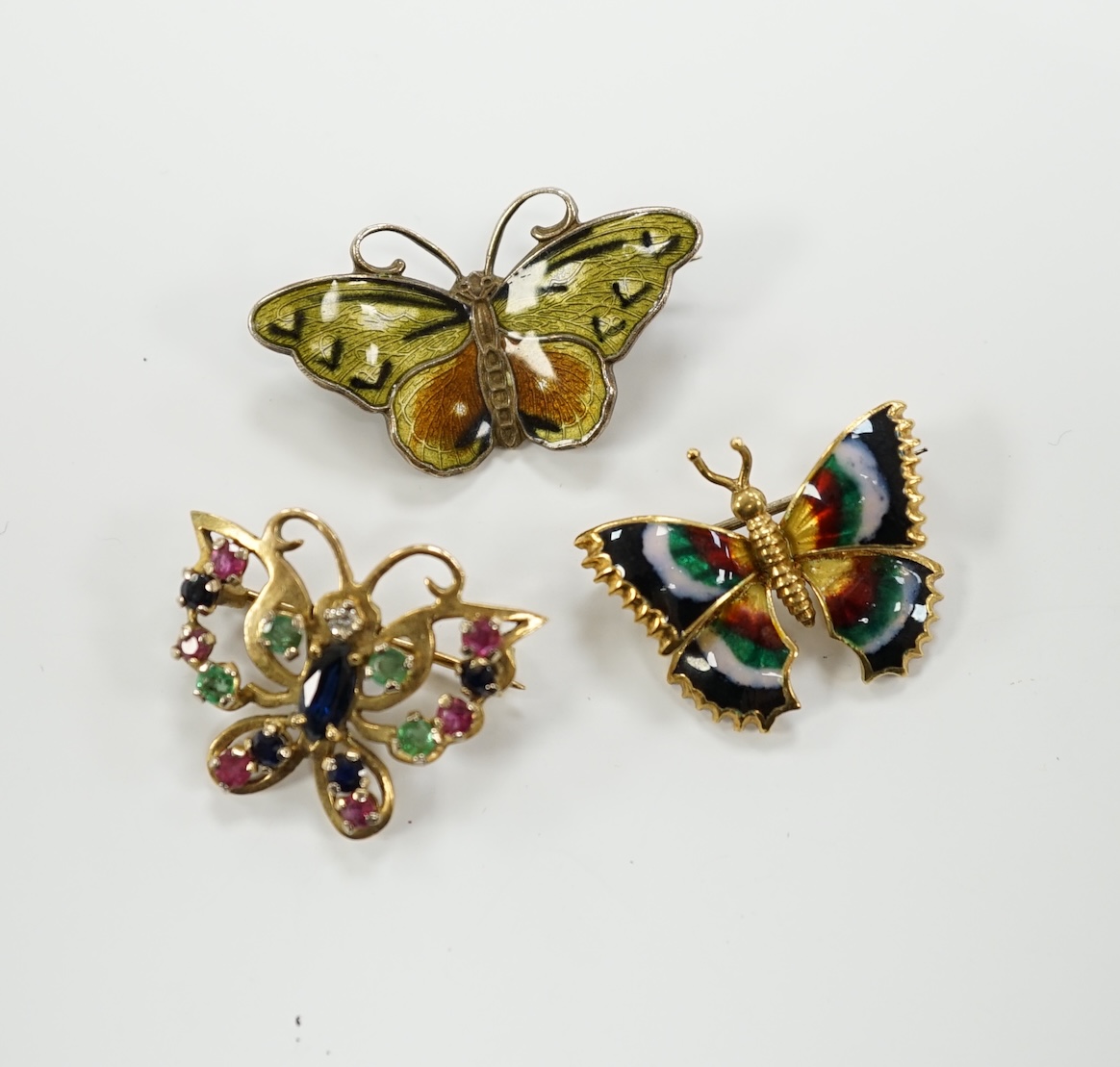 Three assorted butterfly brooches, sterling and enamel, 18k and enamel and 9ct gold and gem set, width 25mm.